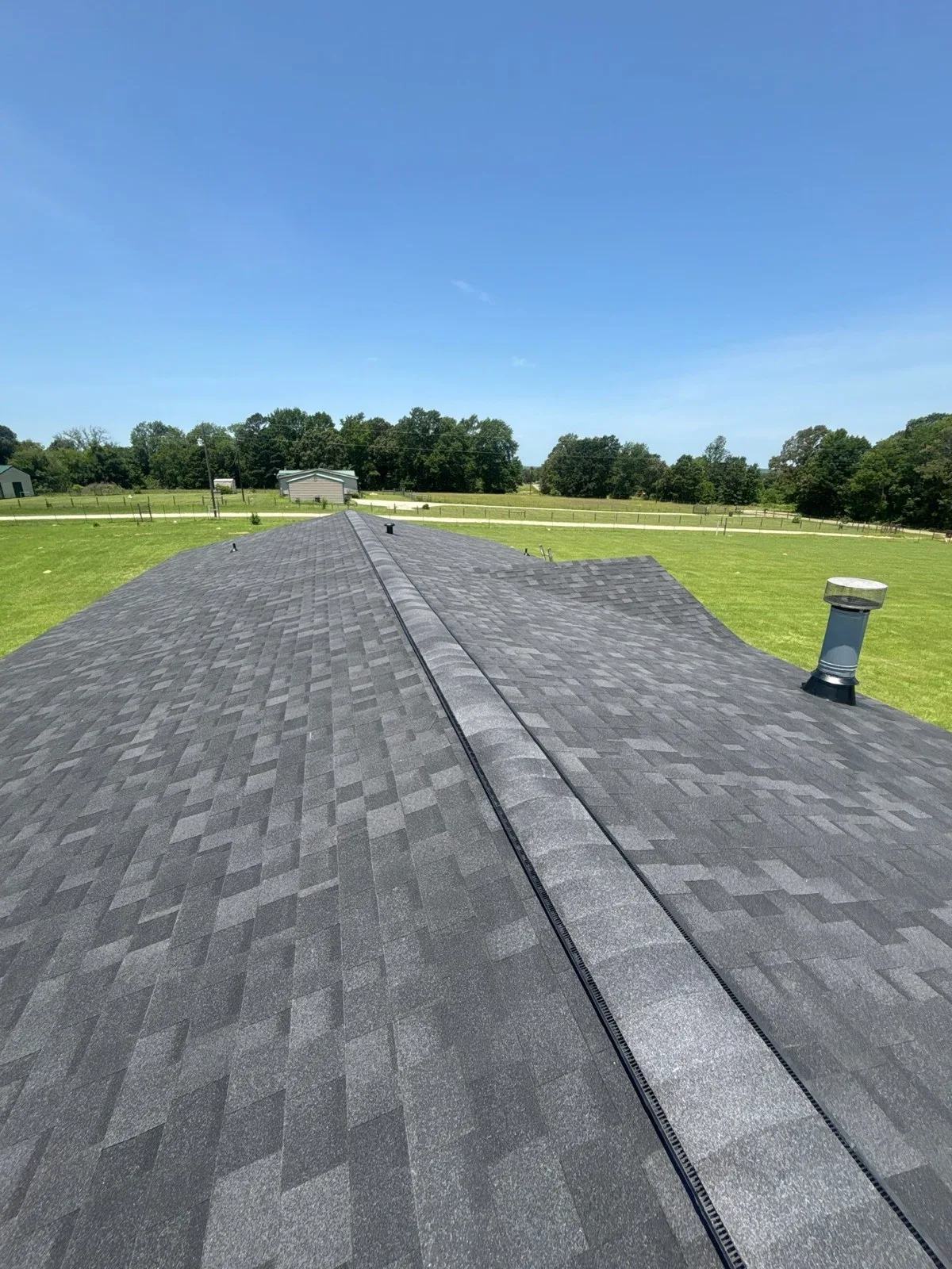 New shingle roof with ridge vent and chimney vent cap on an East Texas ranch property
